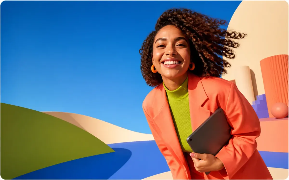 A joyful creative professional holding a tablet in a vivid blue, coral and lime studio