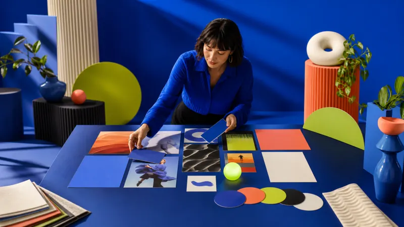 A creative strategist arranging a brand moodboard in a cobalt studio